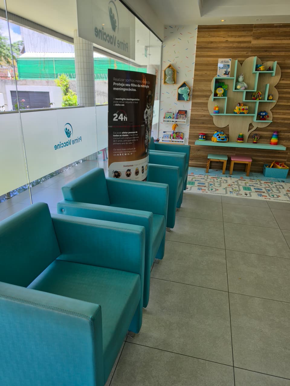 Sala de espera da unidade Poço da Panela com poltronas turquesa e espaço infantil ao fundo