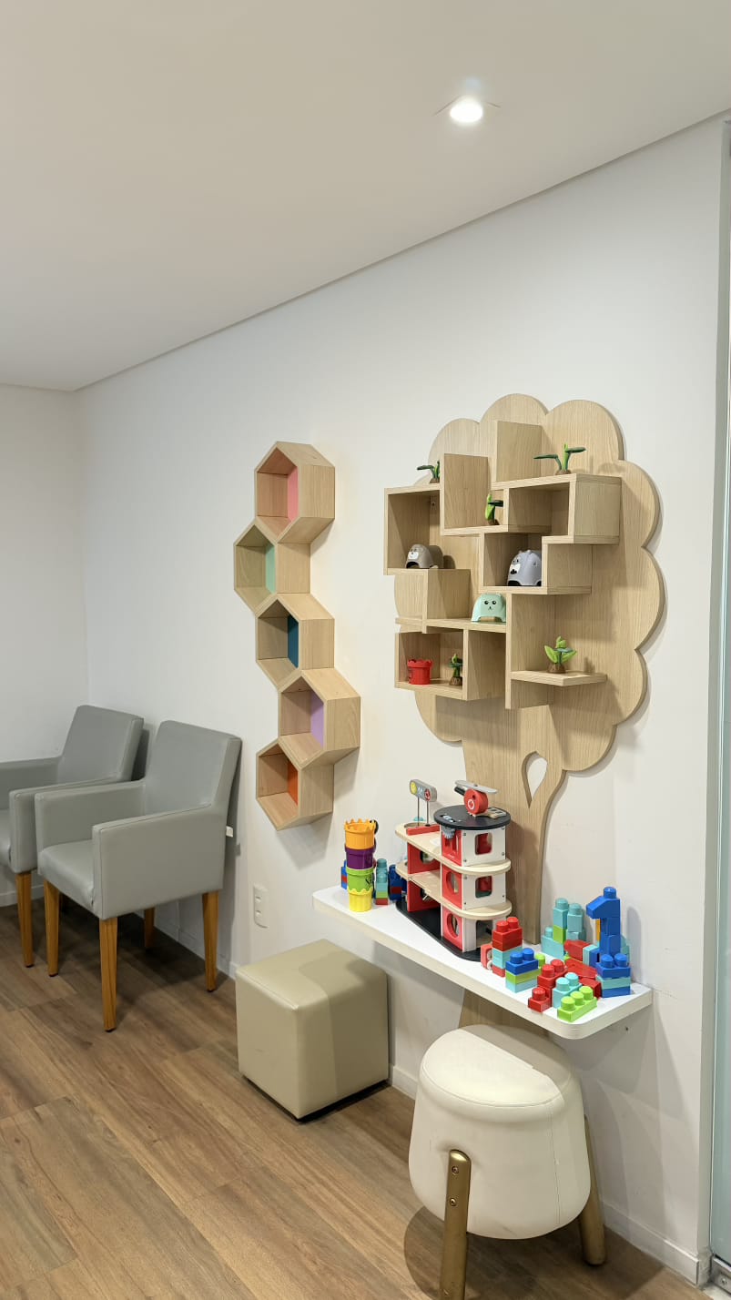 Cantinho infantil da unidade Graças, com estante em formato de árvore, brinquedos e poltronas para acompanhantes
